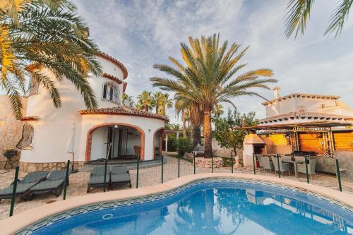 a villa with a swimming pool and palm trees at Villa Helene in Miraflor