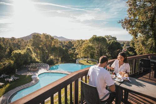 un hombre y una mujer sentados en una mesa en un balcón con vistas a la piscina en Hotel Fonte Santa, en Monfortinho