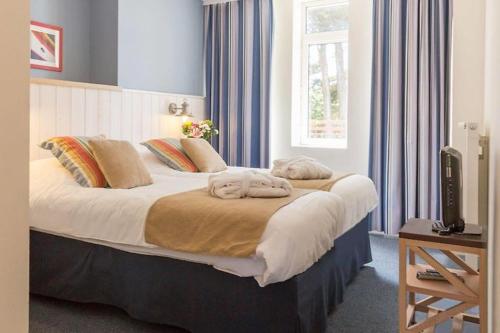 een slaapkamer met een groot bed en blauwe gordijnen bij Appartement de Tamaris (4 pers) in Le Pouliguen