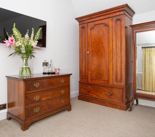 a wooden dresser and a vase of flowers on a dresser at Lords Of The Manor in Upper Slaughter