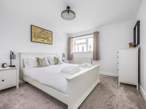 a white bedroom with a white bed and a window at Pass the Keys Stylish Flat Close To Beach in Chichester