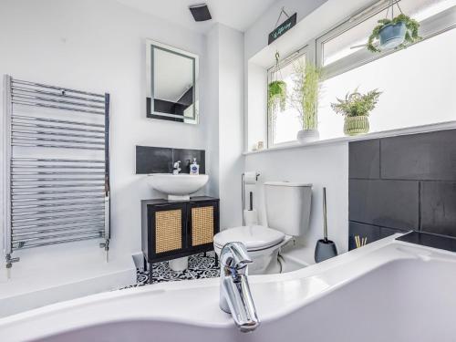 a bathroom with a tub and a toilet and a sink at Pass the Keys Stylish Flat Close To Beach in Chichester