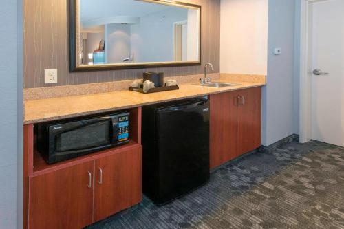 a kitchen with a black microwave and a sink at Courtyard by Marriott Montgomery Prattville in Prattville