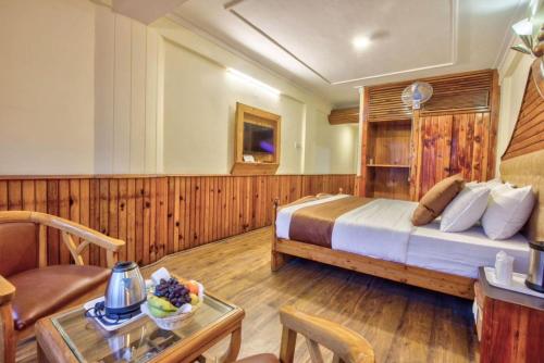 a bedroom with a bed and a table in a room at Goroomgo i Bex Manali Near Mall Road- Best Choice of Travellers in Manāli