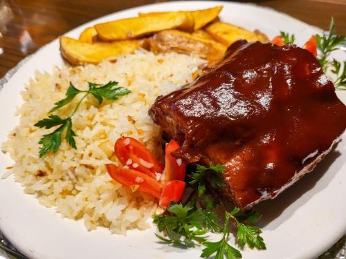 a plate of food with rice and meat and vegetables at Motel Dallas in Belo Horizonte