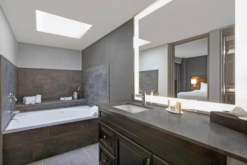 een badkamer met een bad, een wastafel en een spiegel bij Courtyard Chicago Elmhurst/Oakbrook Area in Elmhurst