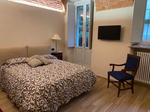 a bedroom with a bed and a chair and a television at Vicolo San Giuseppe 8A e 8B in Alba