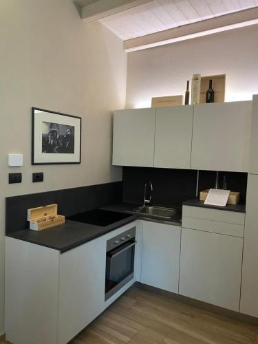 a kitchen with white cabinets and a black counter top at Vicolo San Giuseppe 8A e 8B in Alba