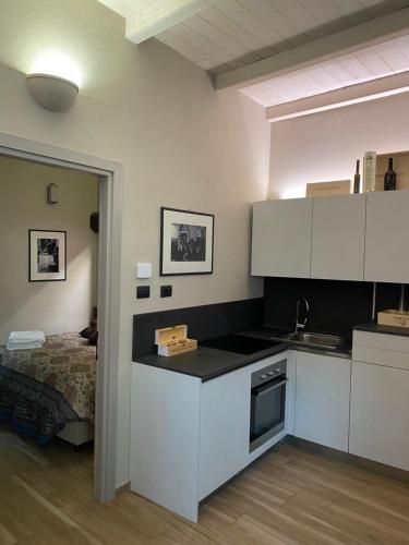 a kitchen with white cabinets and a bed in a room at Vicolo San Giuseppe 8A e 8B in Alba