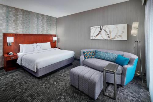 a hotel room with a bed and a couch and a chair at Courtyard By Marriott Baltimore BWI Airport in Linthicum Heights