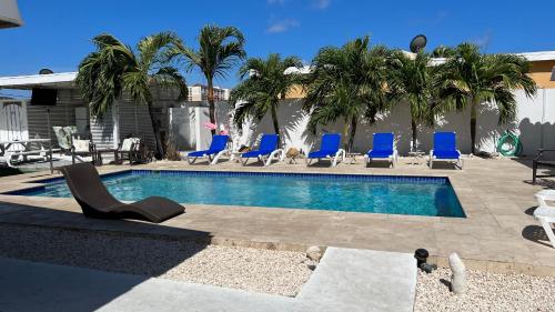 a swimming pool with blue chairs next to a building at Tu Casita en Aruba in Palm-Eagle Beach