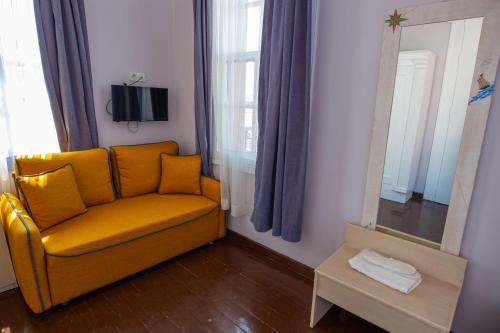 a living room with a yellow chair and a mirror at Deniz Önü Guesthouse in Ayvalık