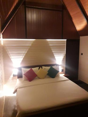 a bedroom with a white bed with colorful pillows at Fair View Cottage in Ella