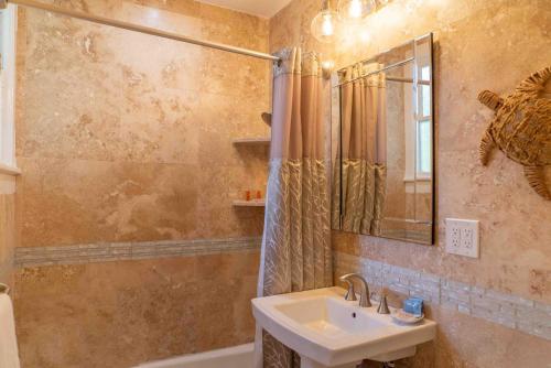 uma casa de banho com um lavatório, um espelho e uma banheira em Southernmost Point Guest House & Garden Bar em Key West