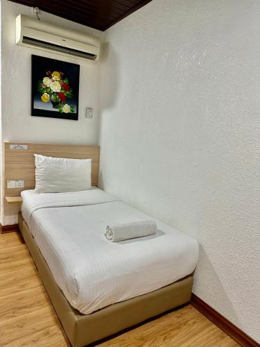 a bed in a room with a white wall at Kangar Hotel Sdn Bhd in Kangar