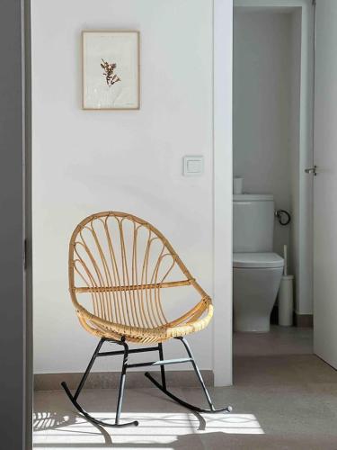 a rattan chair in a bathroom with a toilet at Casa Belladona in Calonge