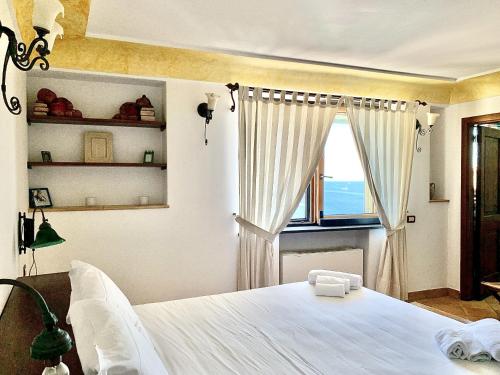 een slaapkamer met een groot wit bed en een raam bij AMORE RENTALS - Casa Vira in Positano