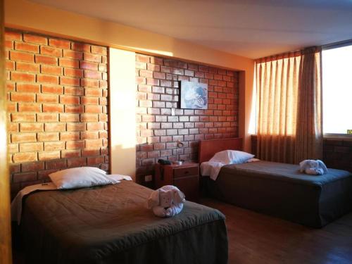 a room with two beds and a brick wall at Meflo Playa Grande in Chala