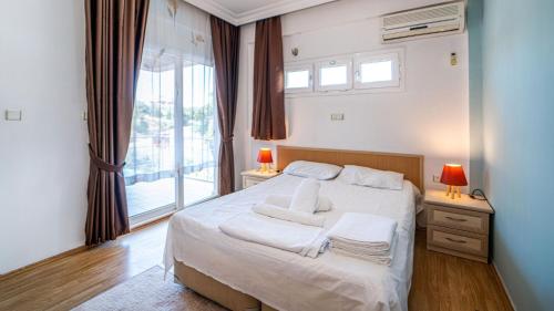 a bedroom with a bed with white sheets and a window at Villa w Terrace 5 min to Lycian Way in Fethiye in Fethiye