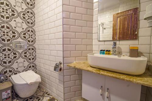 a white bathroom with a sink and a mirror at Bakbay Otel Bozcaada in Çanakkale