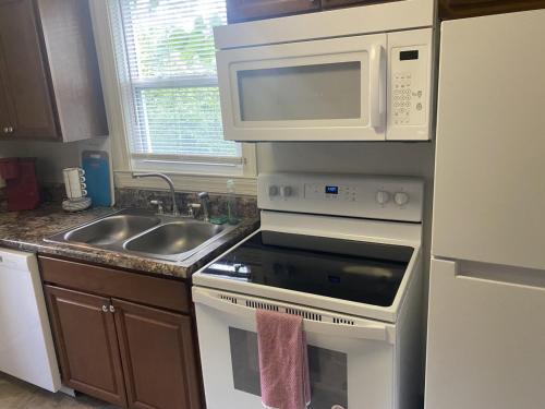 a kitchen with a stove and a microwave and a sink at Luxury Home near South Historic District in Coffeyville