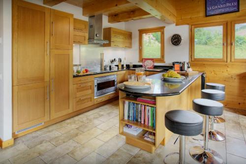 eine Küche mit Holzschränken und eine Insel mit Barhockern in der Unterkunft Chalet Tolar - OVO Network in Le Grand-Bornand