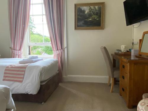 a bedroom with a bed and a desk and a window at Lubnaig Guest House in Callander