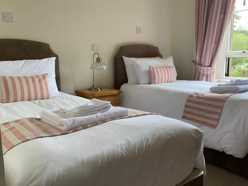 a bedroom with two beds with white sheets and a window at Lubnaig Guest House in Callander