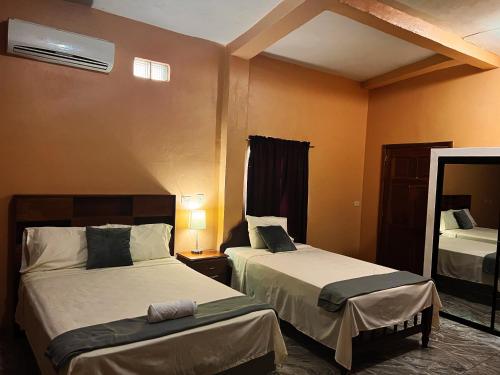 a hotel room with two beds and a window at Hotel y Restaurante La Perla, Cacaopera, Morazan, El Salvador in Cacaopera