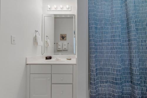 a bathroom with a sink and a blue shower curtain at Sweet Alice's Sandcastle in Navarre