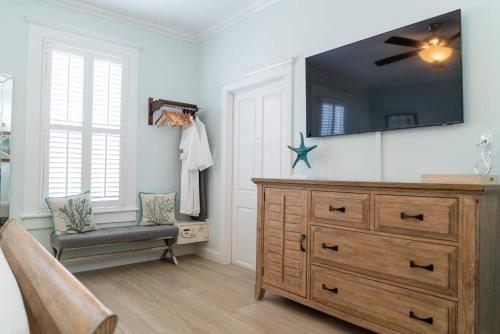 a room with a dresser and a tv on the wall at Southernmost Point Guest House & Garden Bar in Key West