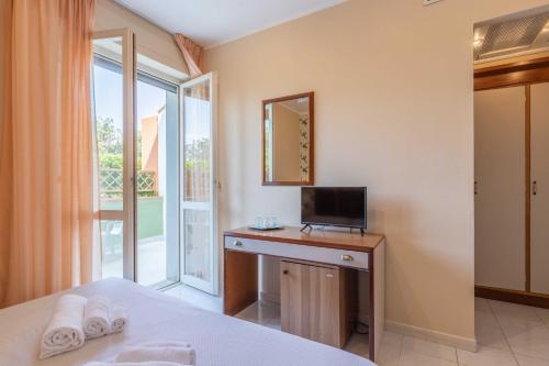 a bedroom with a bed and a desk with a television at Hotel Riva Etrusca in Marina di Bibbona