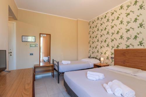 a hotel room with two beds and a tv at Hotel Riva Etrusca in Marina di Bibbona
