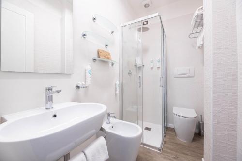 y baño blanco con lavabo y ducha. en Hotel Riva del Sole, en Marina di Campo