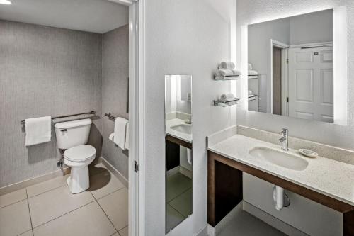 a white bathroom with a toilet and a sink at Residence Inn by Marriott Anchorage Midtown in Anchorage