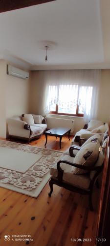 a living room with couches and a table and windows at Kule Apart in Trabzon