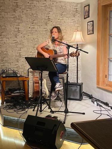 a woman sitting in a room with a guitar and a microphone at Auberge musicale Pour un Instant in La Malbaie