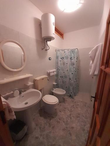 een badkamer met een wastafel, een toilet en een spiegel bij Casa vacanze di Anna in Corsano