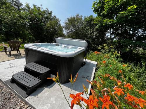 a hot tub sitting on a patio with two benches at Auberge musicale Pour un Instant in La Malbaie