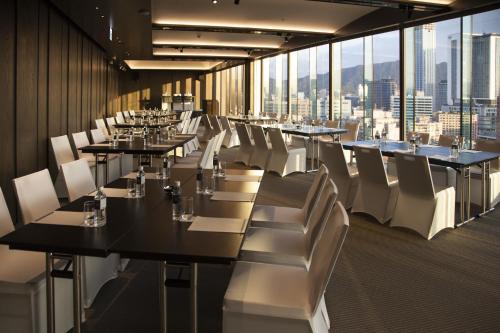 a dining room with tables and white chairs and windows at Eslite Hotel in Taipei