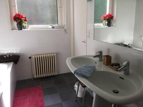 La salle de bains blanche est pourvue d'un lavabo et d'un miroir. dans l'établissement Nausicaà, Apmt bord de mer, 3ch, garage privé, à Boulogne-sur-Mer