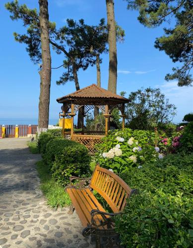 a wooden bench next to a gazebo in a park at Villa ReTa Hotel & SPA in Grigoleti