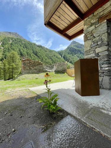 a stone building with a bench on a patio with mountains at La Rêverie de Thumel - Suite in Rhêmes-Notre-Dame