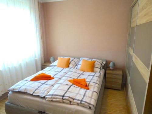 1 dormitorio con 1 cama con almohadas de color naranja en Árkád Apartman-Pécs, en Pécs