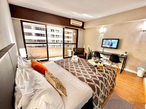 a bedroom with a large bed and a living room at Lindo Studio com Jacuzzi e sacada a 50m Av Paulista in São Paulo