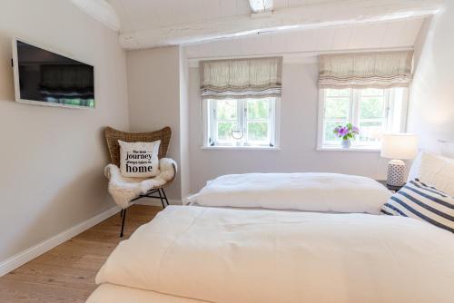 2 camas en un dormitorio con TV y silla en Blä Wening, en Borgsum
