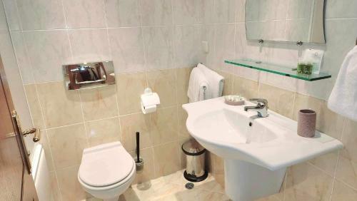 La salle de bains blanche est pourvue de toilettes et d'un lavabo. dans l'établissement Arboro Royal Plaza, à Borovets