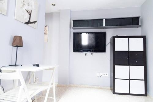 Dieses weiße Zimmer verfügt über einen Schreibtisch und einen TV an der Wand. in der Unterkunft Pasquín in Cádiz