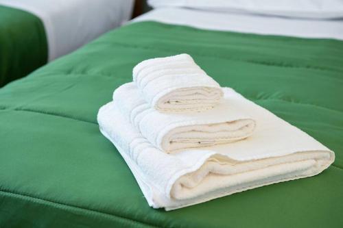una pila de toallas sentadas en una cama verde en Bellagio Dreams,Luxury Apartment, en Bellagio