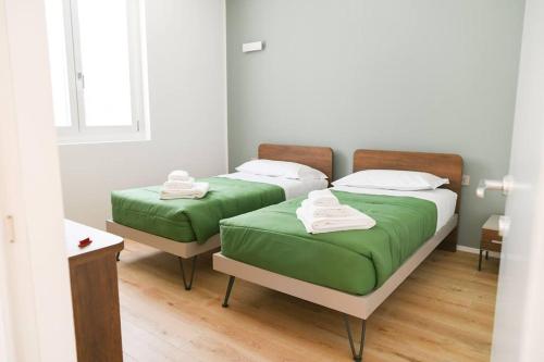 two beds with green sheets in a room at Bellagio Dreams,Luxury Apartment in Bellagio